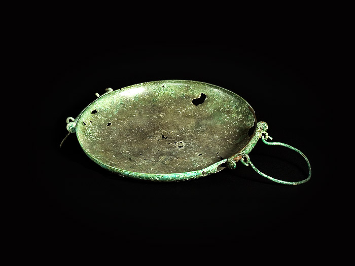  Patera in bronzo a bassa calotta emisferica con ansa in verga di bronzo.
