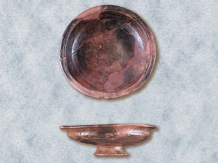Due piatti in impasto bruno, rilisciati a stecca, su basso piede a tromba. 